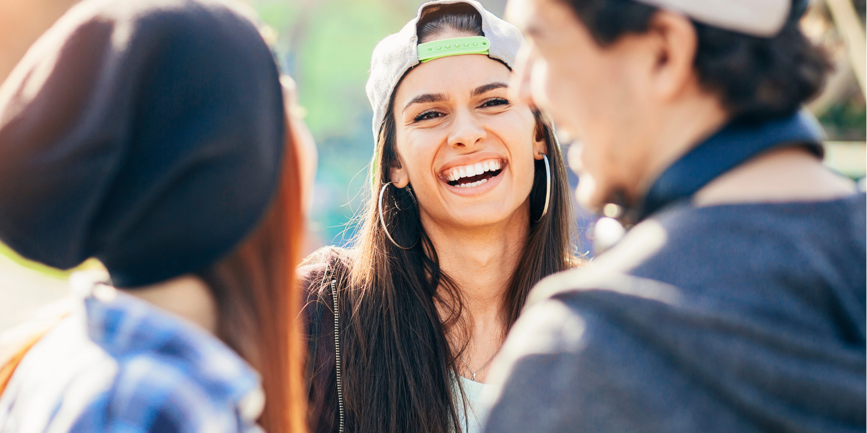 3 junge Menschen stehen beisammen und lachen