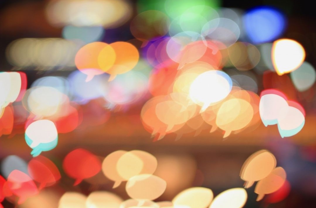 Eine leicht verschwommene Aufnahme auf der bunte Lichter in Form von Sprechblasen zu sehen sind.